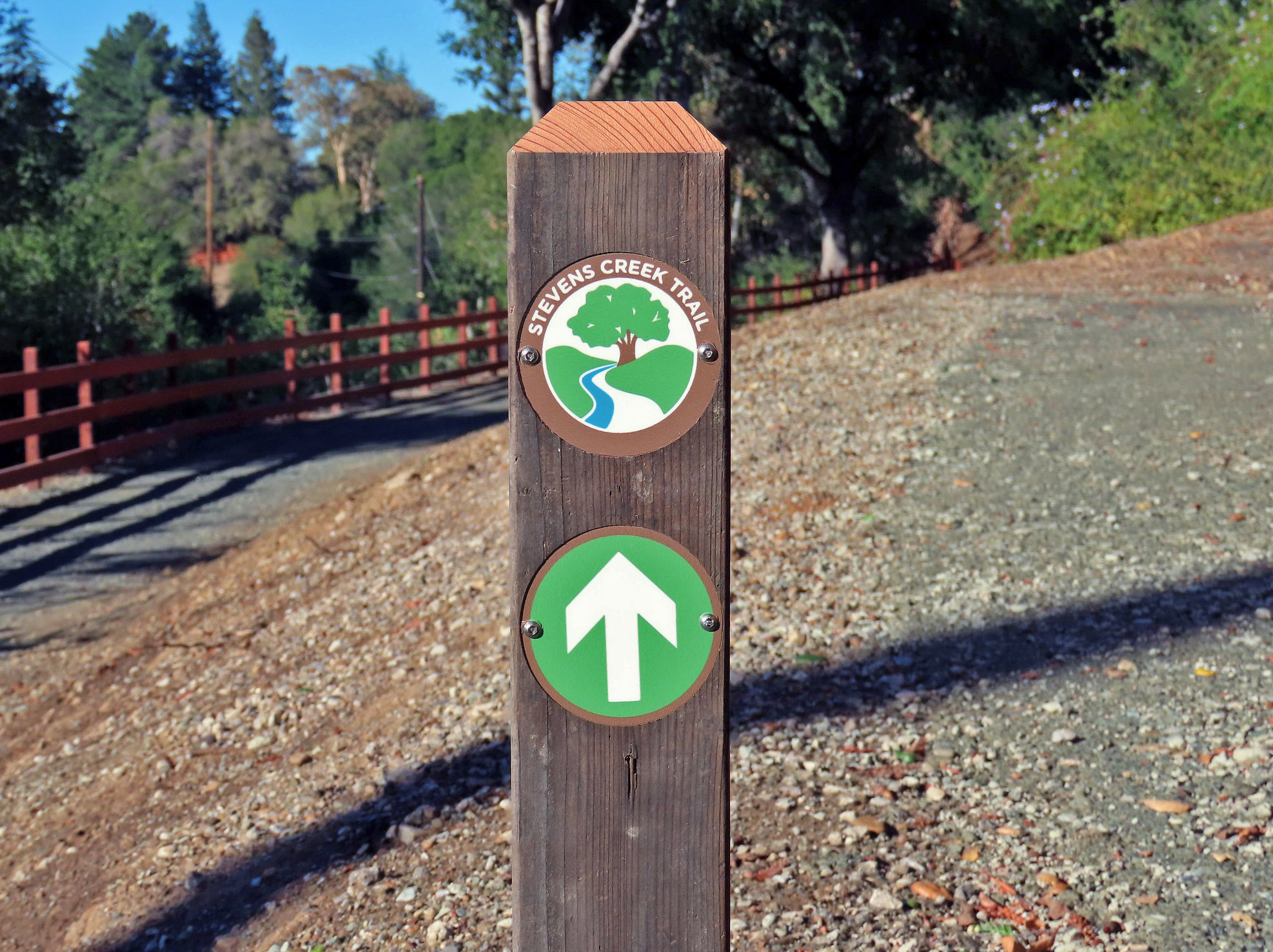 Photo of post with Stevens Creek Trail medallion and directional arrow pointing up